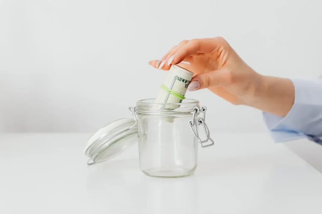 Basics of emergency funds: Placing cash in a jar for financial security.
