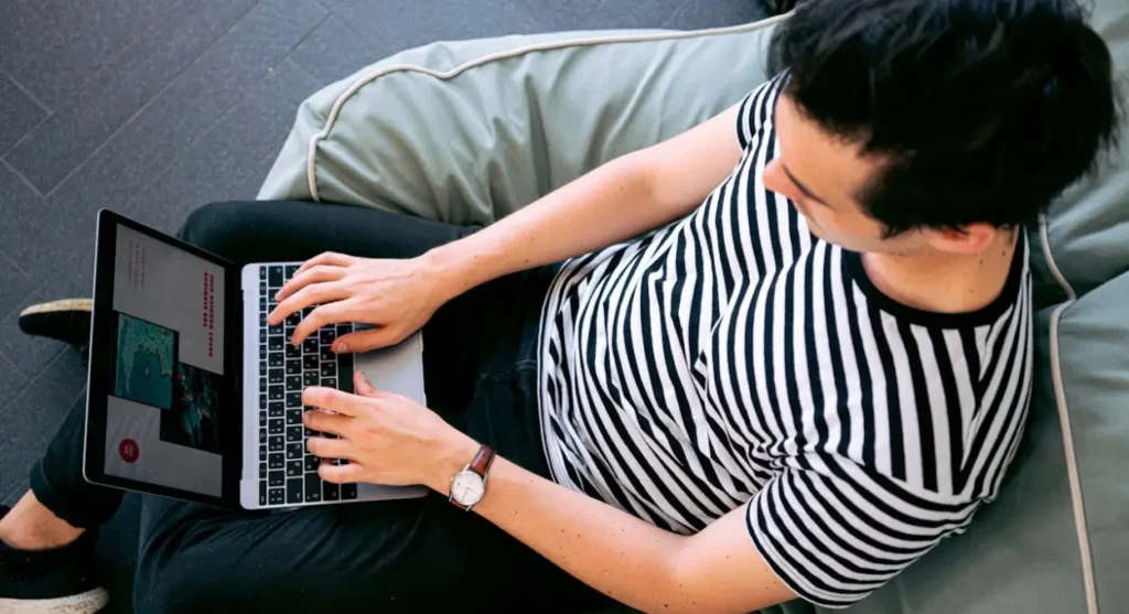 Freelancer working on a laptop while relaxing on Freelancer working on a laptop while relaxing on a bean bag, representing the flexibility and independence of remote work and financial planning.